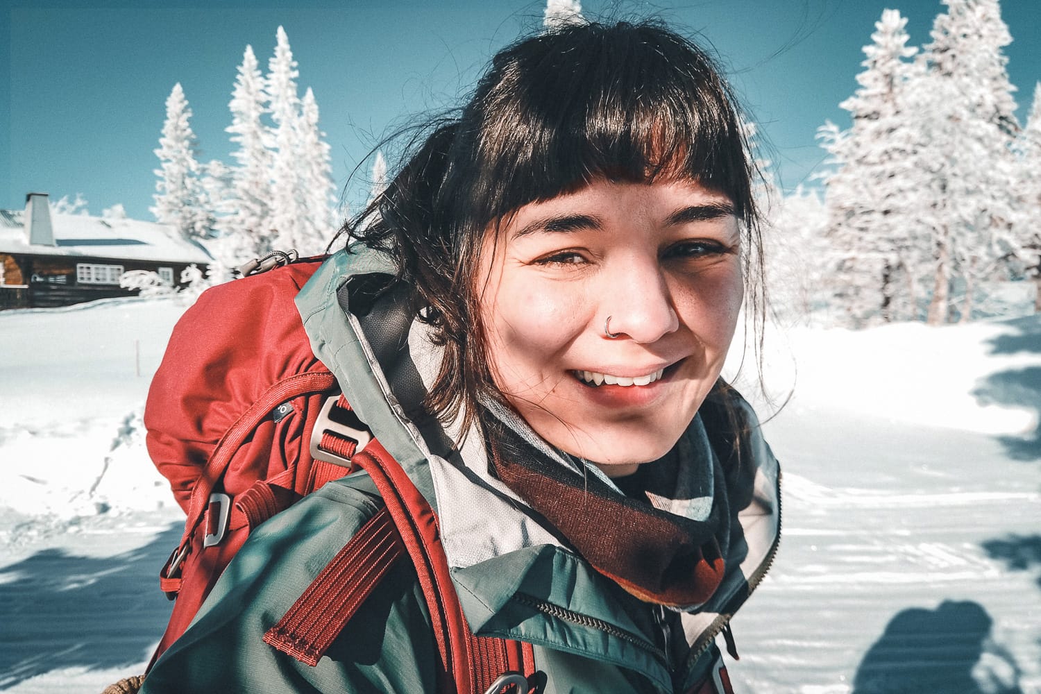 Woman with backpack smiling in the winter sun
