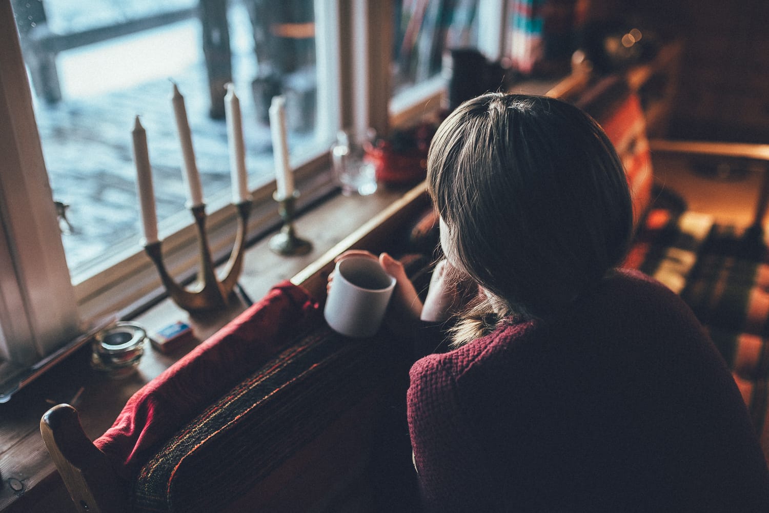 woman enjoying coffee by a cabin window