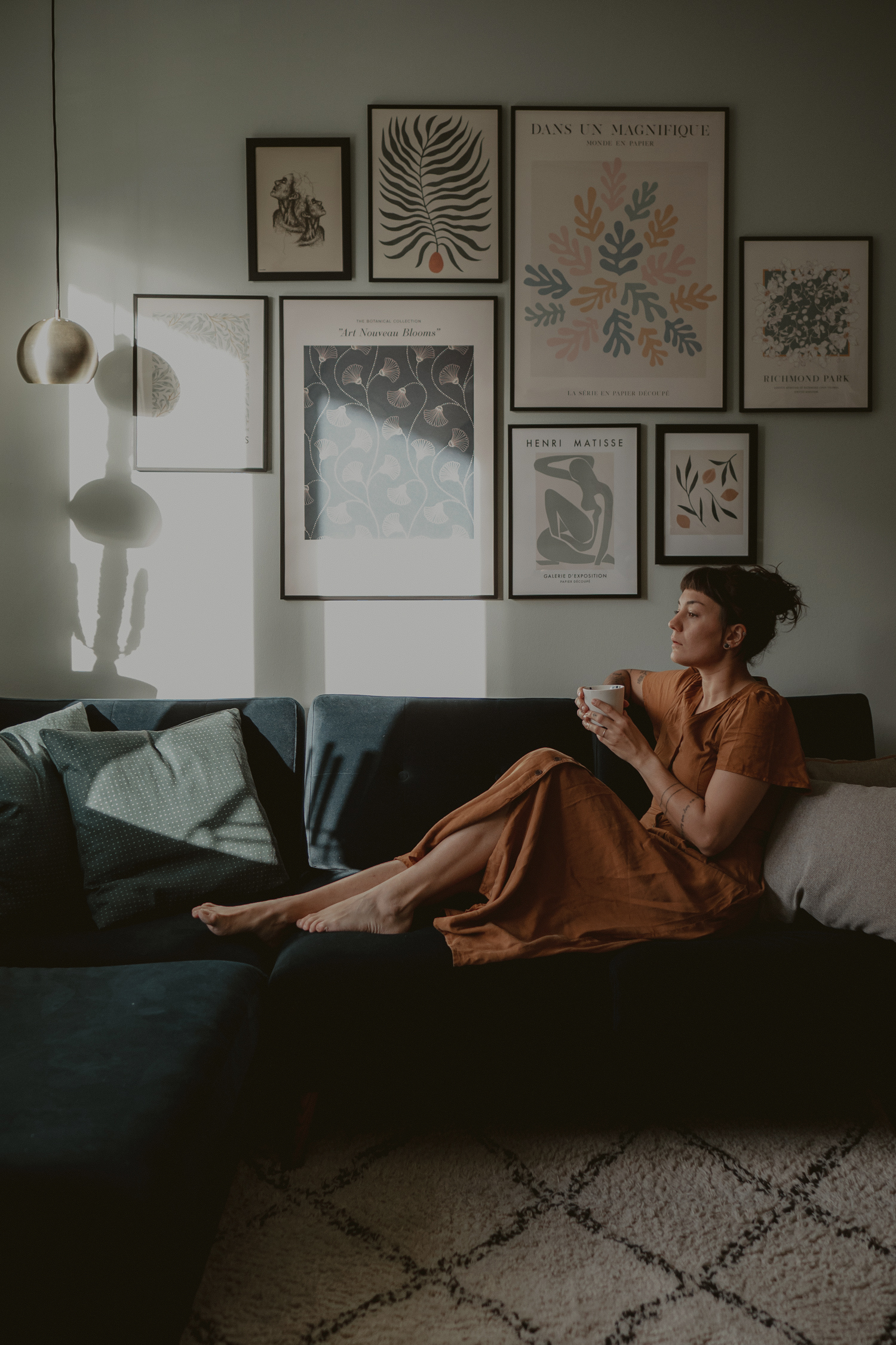 woman in rust coloured dress on couch with coffee