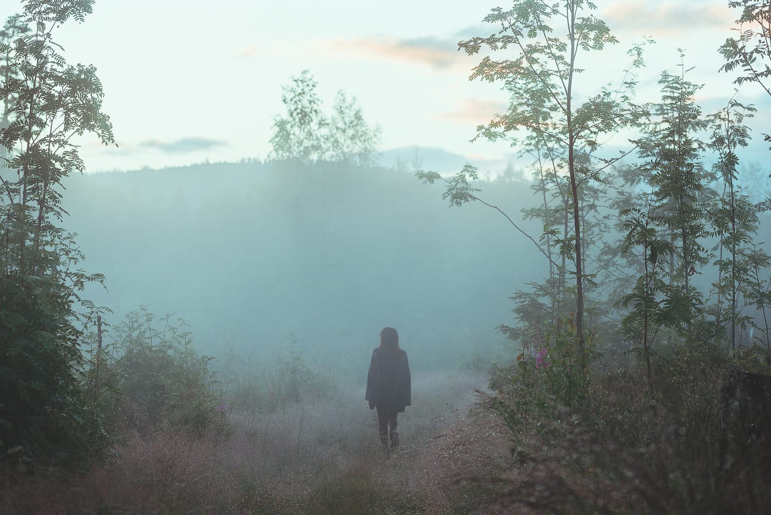 a woman walking in a foggy forest