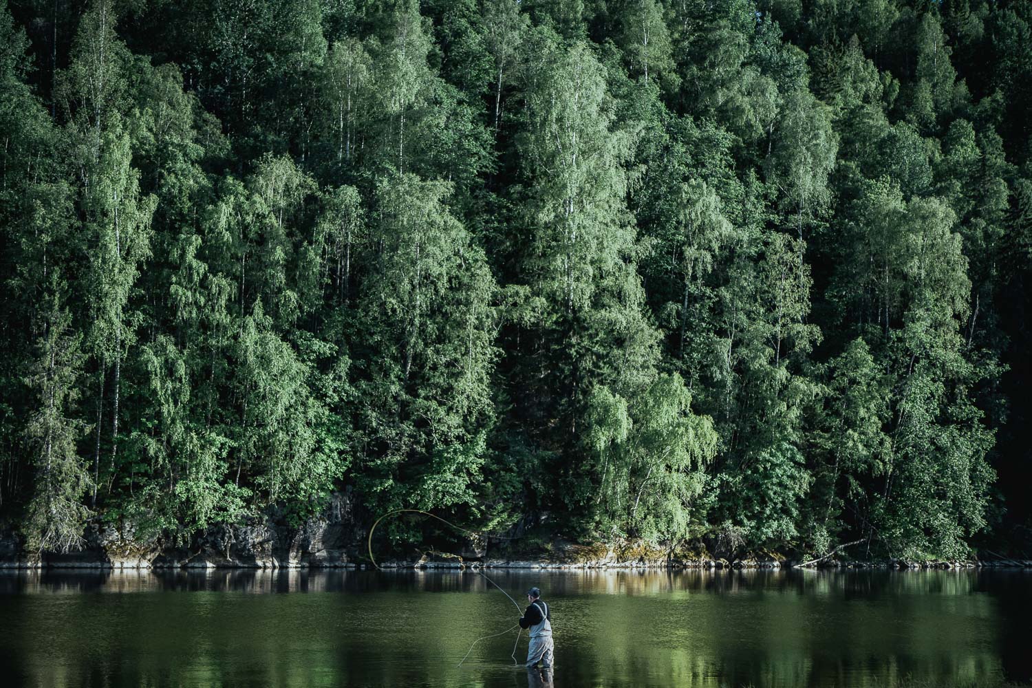 man fly fishing in a river