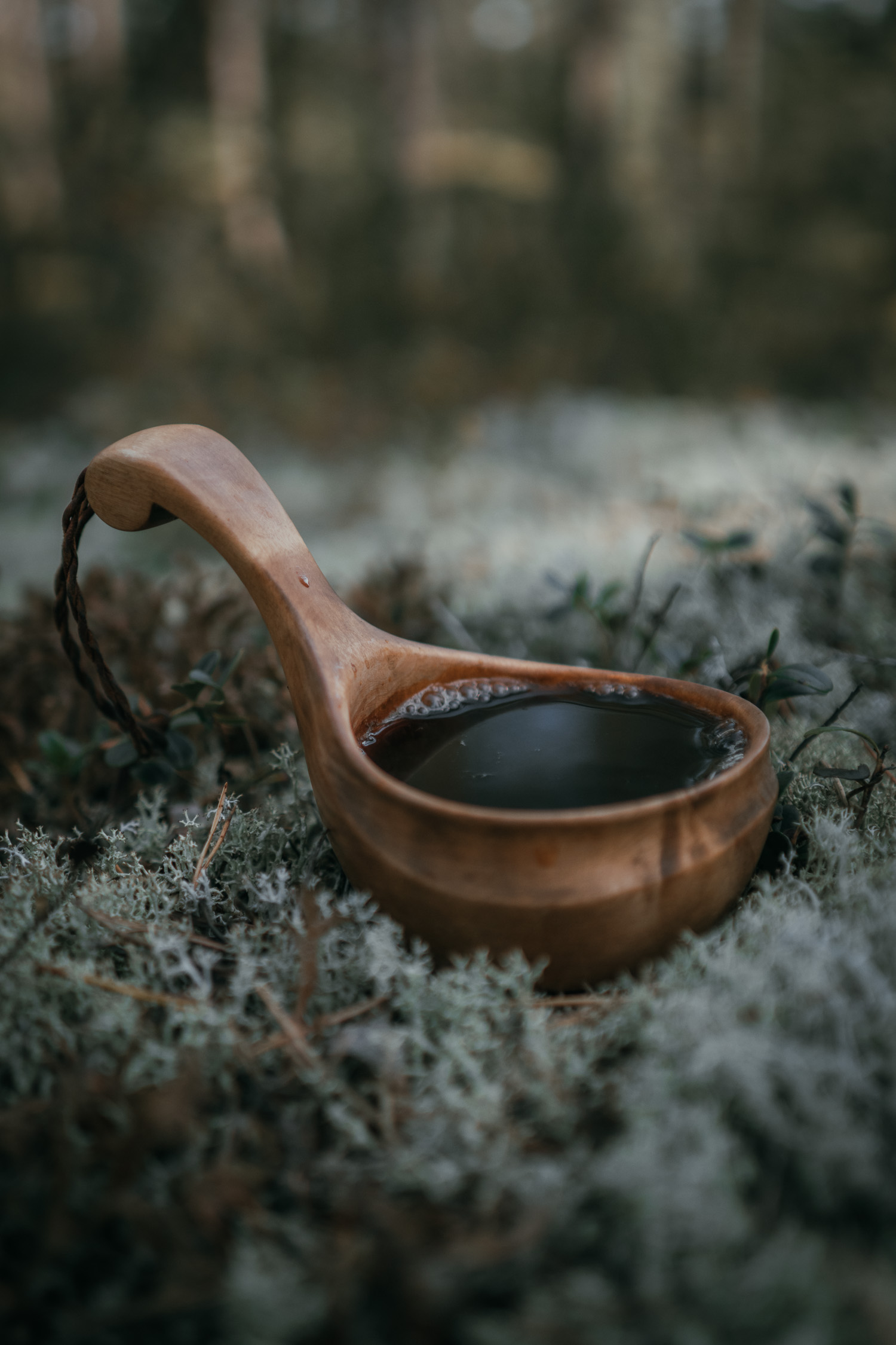 a wooden cup with coffee in white reindeer moss